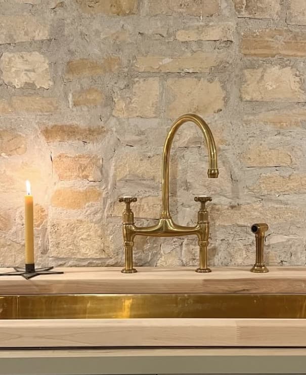 Unlacquered brass tap against a stone wall