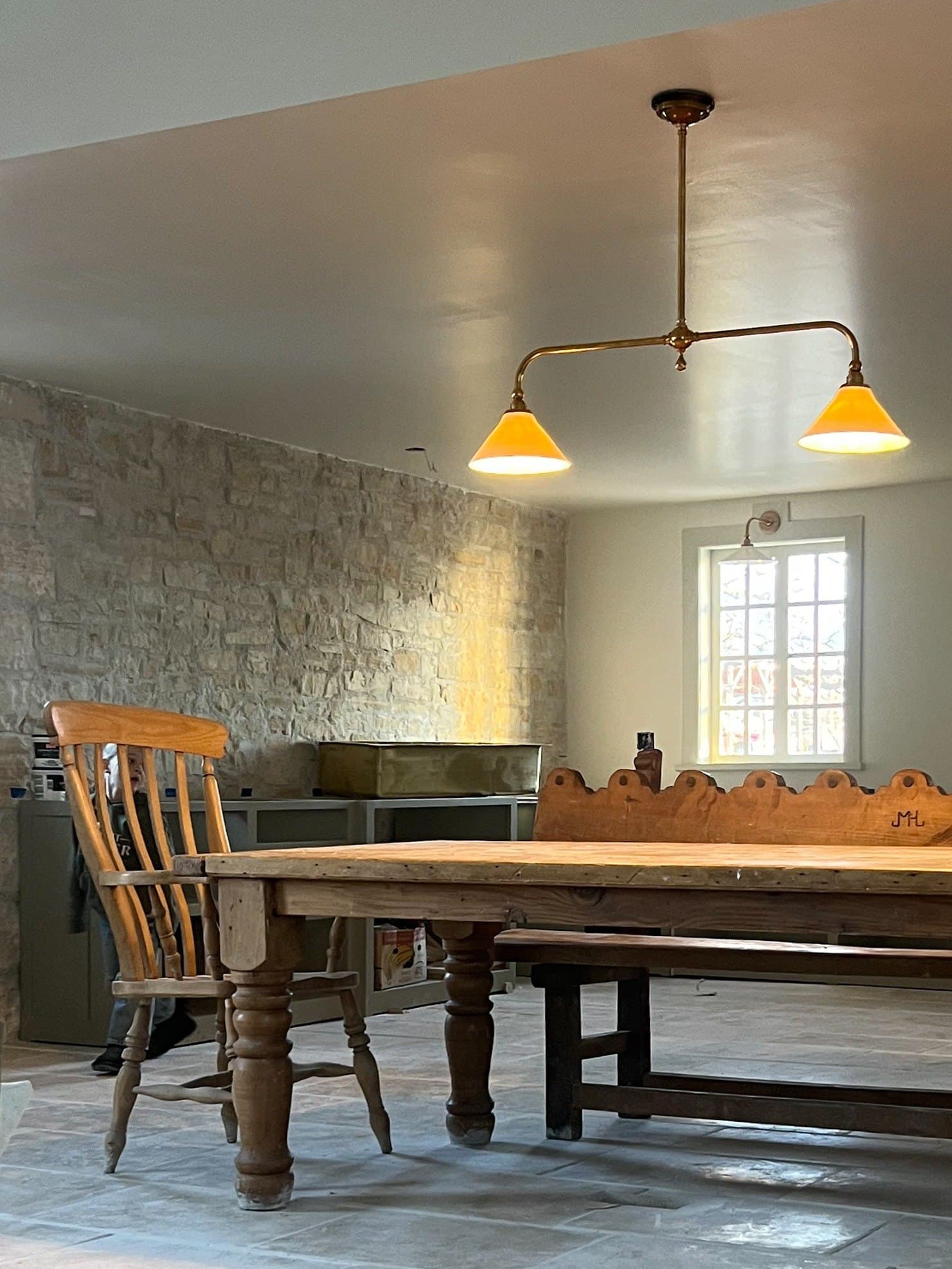 Kitchen with exposed stone wall and brass pendants