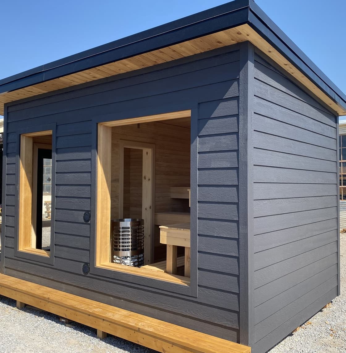 A completed cabin with the sauna stove and cedar benches visible through the glazing